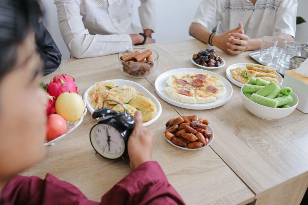 Group of people sitting at a table with plates of food and a clock, representing intermittent fasting, reset metabolism fasting, and lifestyle approaches similar to Kirkland Weight Loss strategies.