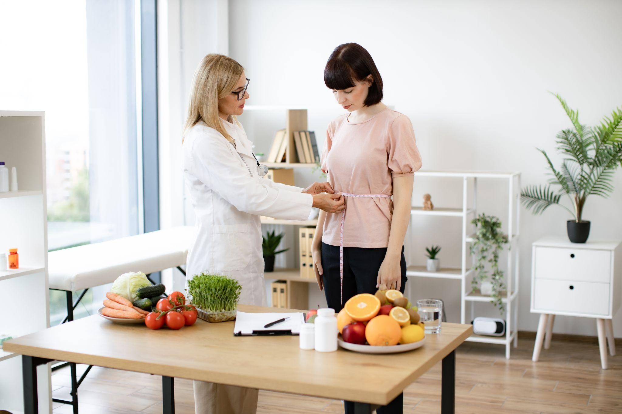 Female doctor measuring patient's waist during a real food weight loss consultation at a Kirkland weight loss clinic.